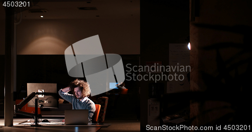 Image of man working on computer in dark office