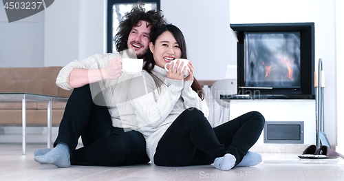 Image of multiethnic romantic couple  in front of fireplace