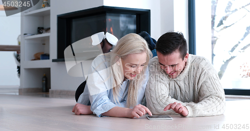 Image of Young Couple using digital tablet on the floor