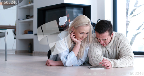 Image of Young Couple using digital tablet on the floor