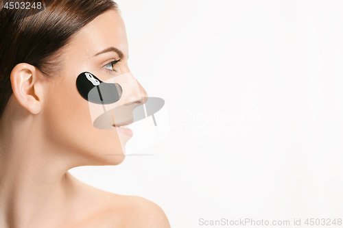 Image of Young beautiful woman applying a mask for the face of the therapeutic black mud. Spa treatment