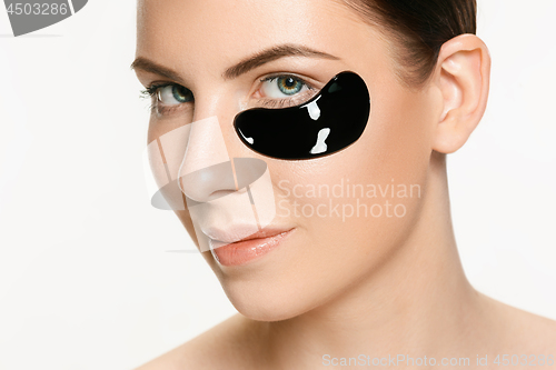 Image of Young beautiful woman applying a mask for the face of the therapeutic black mud. Spa treatment