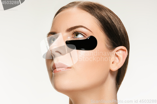 Image of Young beautiful woman applying a mask for the face of the therapeutic black mud. Spa treatment