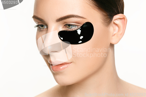 Image of Young beautiful woman applying a mask for the face of the therapeutic black mud. Spa treatment