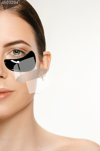 Image of Young beautiful woman applying a mask for the face of the therapeutic black mud. Spa treatment