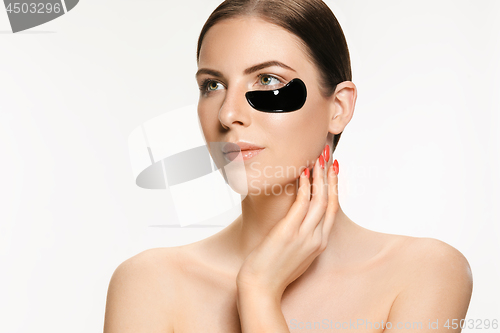 Image of Young beautiful woman applying a mask for the face of the therapeutic black mud. Spa treatment