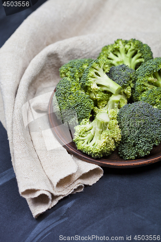 Image of Fresh green organic broccoli in brown plate and linen napkin 