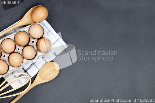 Image of Fresh eggs and kitchen utensil on backboard background. 