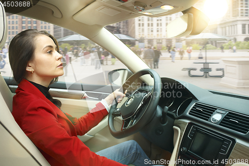 Image of Driving around city. Young attractive woman driving a car