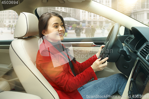 Image of Driving around city. Young attractive woman driving a car