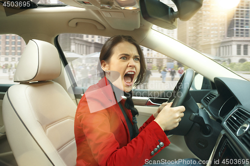 Image of Driving around city. Young attractive woman driving a car