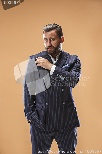 Image of Male beauty concept. Portrait of a fashionable young man with stylish haircut wearing trendy suit posing over pastel background.