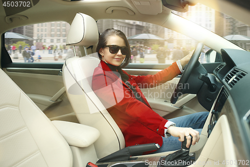 Image of Driving around city. Young attractive woman driving a car