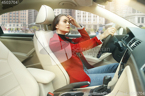 Image of Driving around city. Young attractive woman driving a car