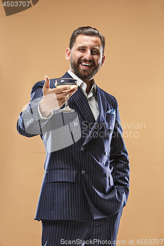 Image of Smiling young businesman with glass of champagne standing and celebrating over pastel background