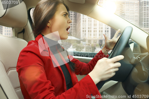 Image of Driving around city. Young attractive woman driving a car