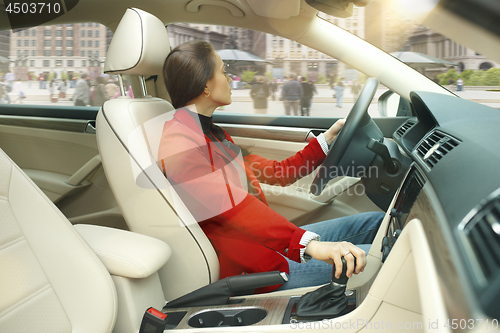 Image of Driving around city. Young attractive woman driving a car