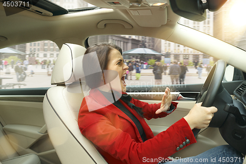 Image of Driving around city. Young attractive woman driving a car