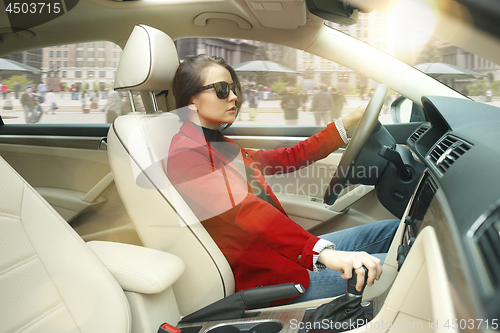 Image of Driving around city. Young attractive woman driving a car