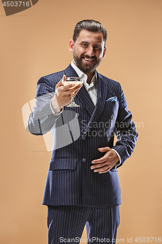 Image of Smiling young businesman with glass of champagne standing and celebrating over pastel background