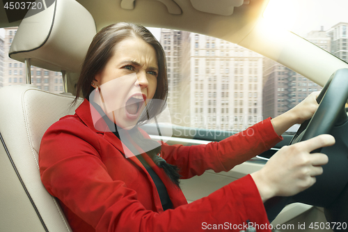 Image of Driving around city. Young attractive woman driving a car