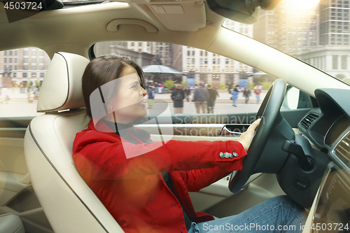Image of Driving around city. Young attractive woman driving a car