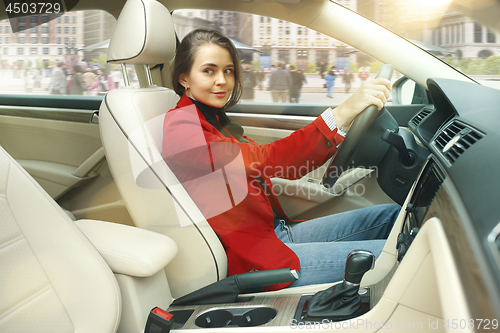 Image of Driving around city. Young attractive woman driving a car
