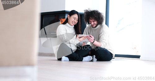 Image of Young Couple using digital tablet on the floor