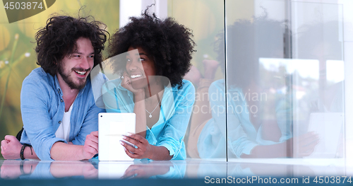 Image of Couple relaxing together at home with tablet computer