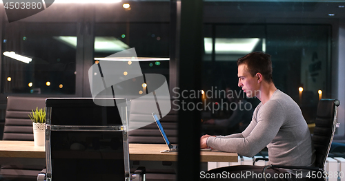 Image of man working on laptop in dark office