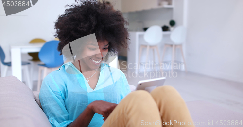 Image of african american woman at home using digital tablet