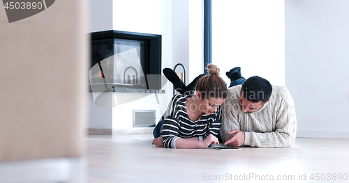 Image of Young Couple using digital tablet on the floor