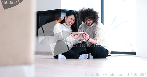 Image of Young Couple using digital tablet on the floor