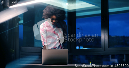 Image of black businesswoman using a laptop in night startup office