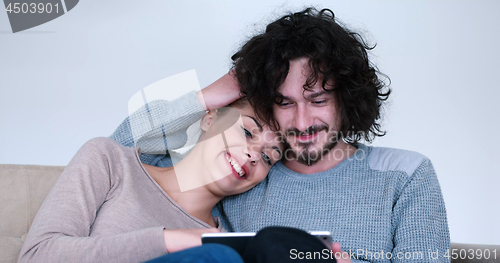 Image of couple relaxing at  home with tablet computers
