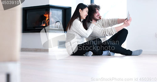 Image of Young Couple using digital tablet on the floor