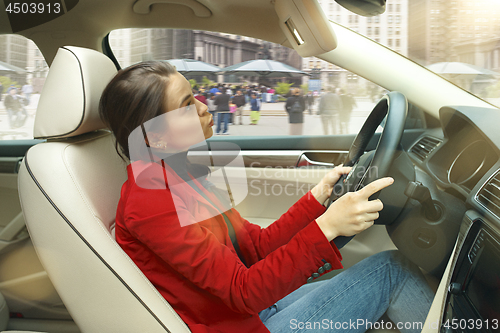 Image of Driving around city. Young attractive woman driving a car