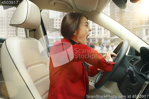 Image of Driving around city. Young attractive woman driving a car