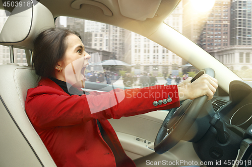 Image of Driving around city. Young attractive woman driving a car