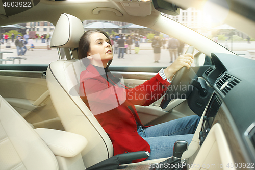 Image of Driving around city. Young attractive woman driving a car