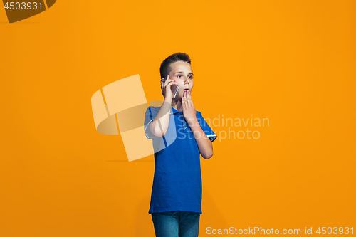 Image of The happy teen boy standing and smiling against orange background.