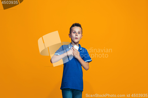 Image of The happy teen boy standing and smiling against orange background.