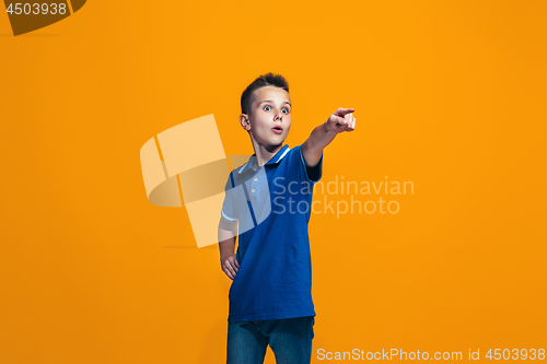 Image of The happy teen boy pointing to you, half length closeup portrait on orange background.