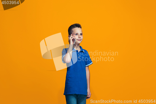 Image of The happy teen boy standing and smiling against orange background.