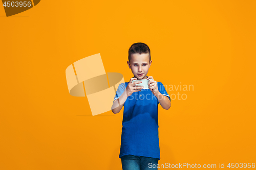 Image of The happy teen boy standing and smiling against orange background.