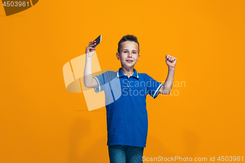 Image of The happy teen boy standing and smiling against orange background.