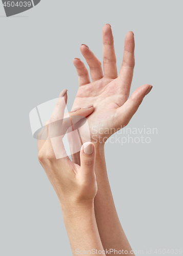 Image of Beautiful women hands applying cream on a gray background. Process of hands massage. Hand skin care. Close up.