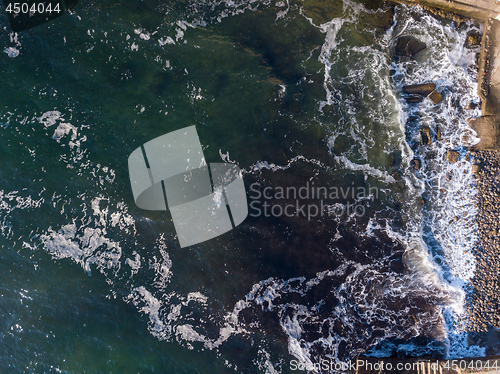 Image of Aerial top view to a stone beach of seashore, turquoise water and crashing foam waves. Top view from drone. Place for text.