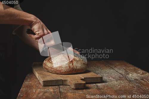Image of Man slicing tasty fresh bread.