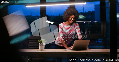 Image of black businesswoman using a laptop in night startup office